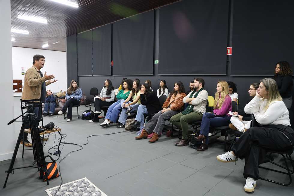 Aula de atuação com turma sentada e professor conduzindo